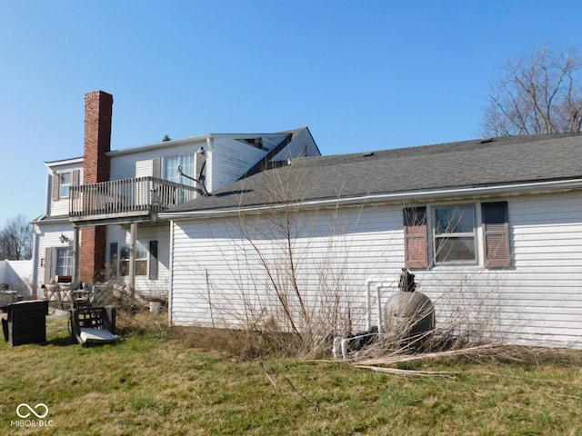 view of side of home with a yard and a balcony