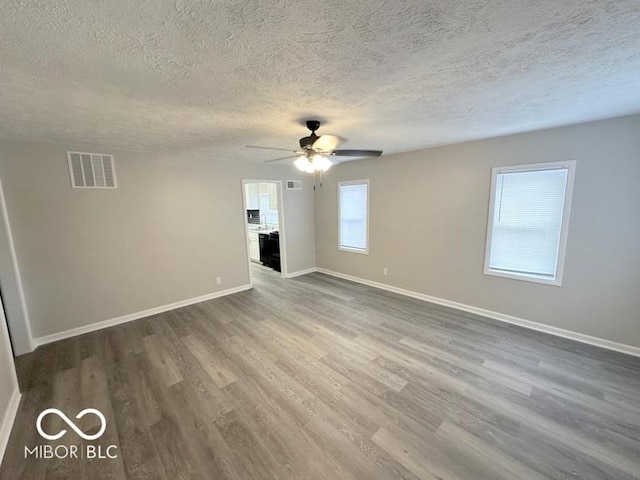 unfurnished living room featuring ceiling fan, wood-type flooring, and a textured ceiling