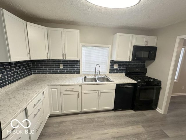 kitchen with black appliances, white cabinetry, sink, and a textured ceiling