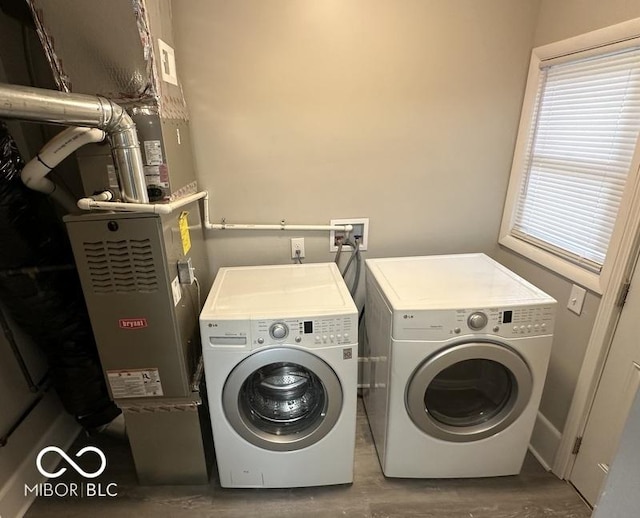 clothes washing area with washer and clothes dryer and hardwood / wood-style flooring