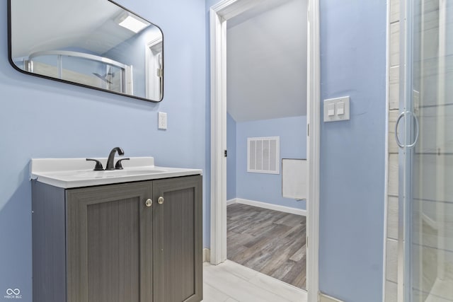 bathroom featuring hardwood / wood-style floors, vanity, a shower with door, and vaulted ceiling