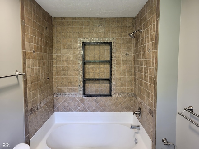 bathroom featuring tiled shower / bath combo and a textured ceiling