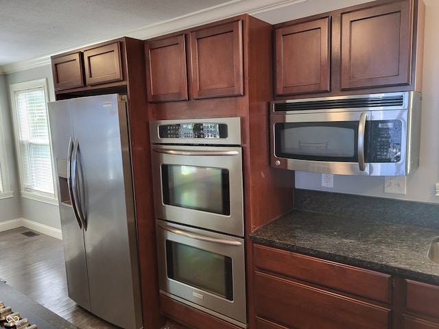 kitchen featuring hardwood / wood-style flooring, stainless steel appliances, and dark stone counters