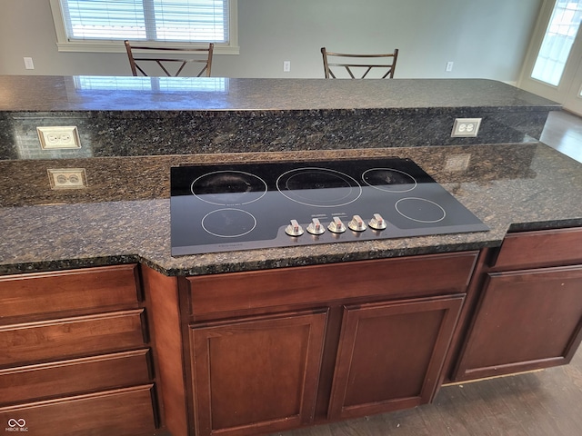 kitchen with dark hardwood / wood-style flooring, stainless steel gas cooktop, and dark stone counters