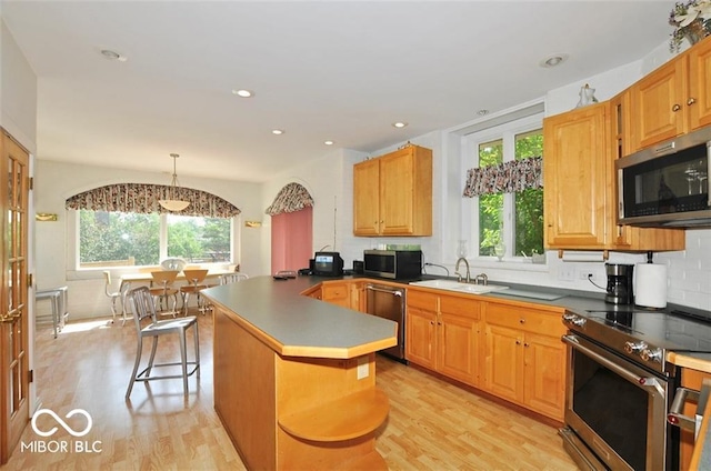 kitchen with a wealth of natural light, a breakfast bar, stainless steel appliances, and light wood-type flooring