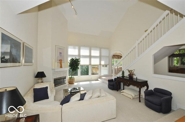 living room with light carpet, a fireplace, high vaulted ceiling, and track lighting