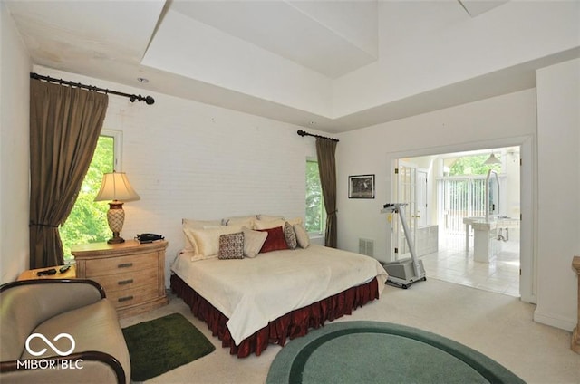 bedroom with light carpet, a tray ceiling, and multiple windows