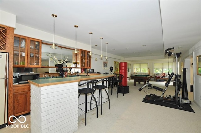 interior space featuring light colored carpet, hanging light fixtures, billiards, and fridge