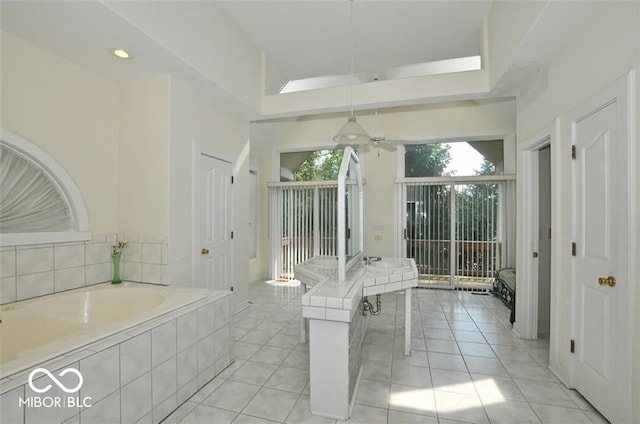 bathroom with tile patterned flooring, ceiling fan, and tiled tub