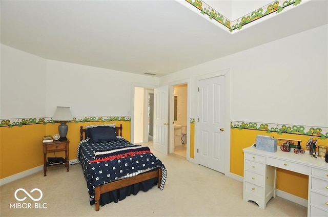 bedroom featuring ensuite bathroom and light colored carpet