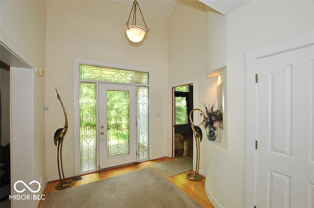 doorway to outside with hardwood / wood-style floors and a towering ceiling