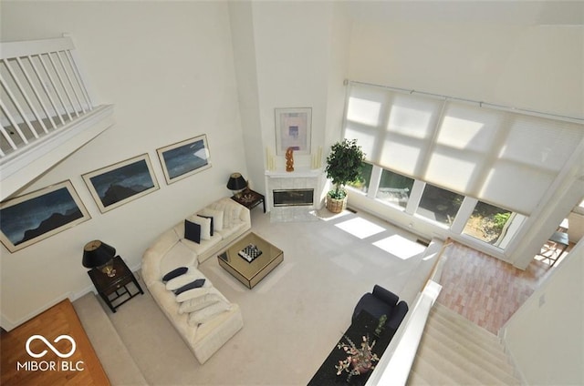 living room featuring a tile fireplace, a towering ceiling, and wood-type flooring