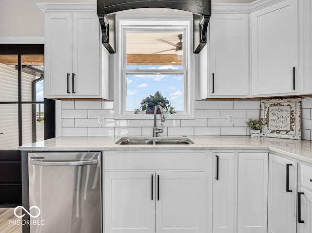 kitchen with light stone countertops, dishwasher, sink, backsplash, and white cabinets