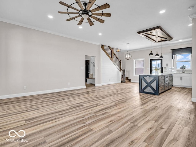 unfurnished living room with crown molding, sink, ceiling fan, and light hardwood / wood-style floors