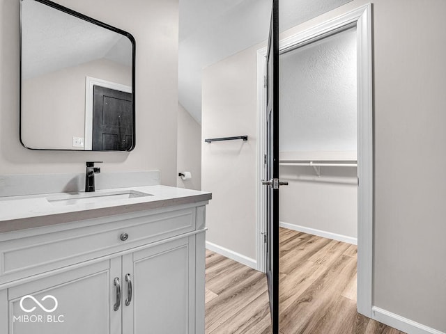 bathroom with vanity, wood-type flooring, and lofted ceiling