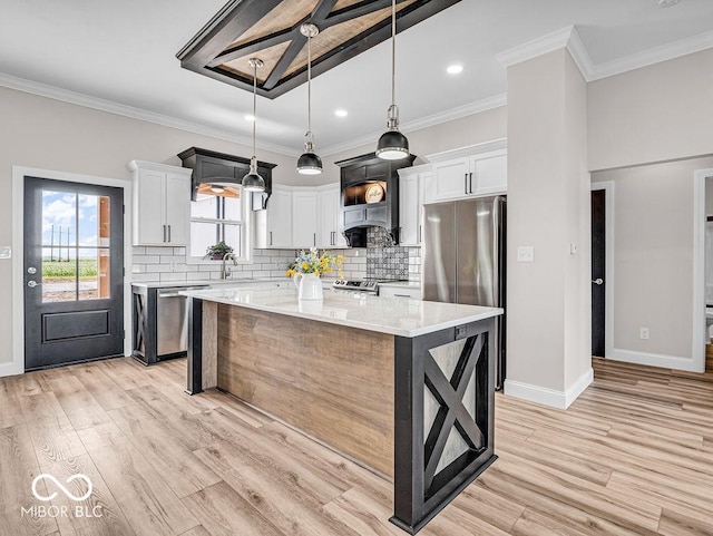 kitchen featuring light stone countertops, stainless steel appliances, white cabinets, a kitchen island, and hanging light fixtures