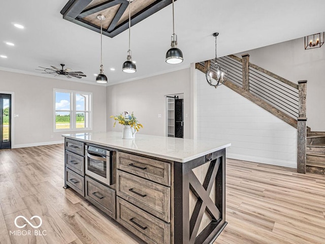 kitchen with light stone counters, a kitchen island, light hardwood / wood-style floors, and decorative light fixtures