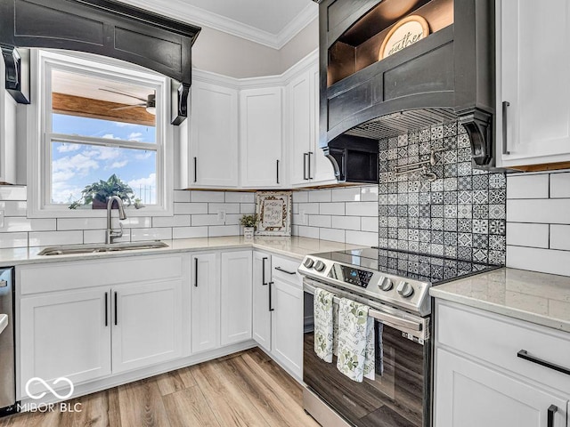 kitchen featuring light stone counters, custom range hood, stainless steel appliances, sink, and white cabinets