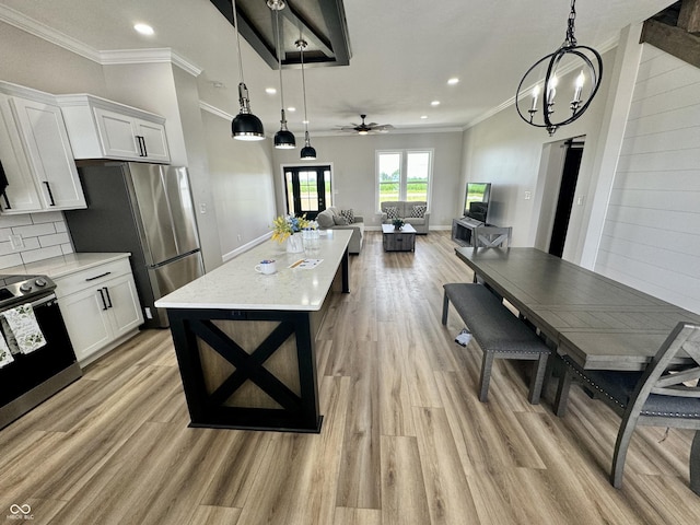 kitchen featuring white cabinets, appliances with stainless steel finishes, backsplash, and ceiling fan with notable chandelier