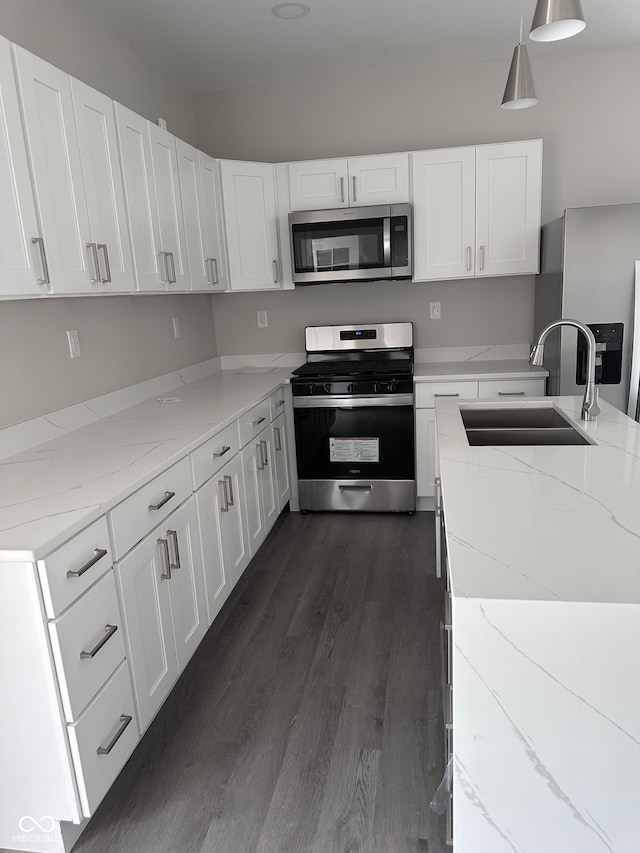 kitchen featuring white cabinetry, hanging light fixtures, appliances with stainless steel finishes, dark hardwood / wood-style floors, and sink