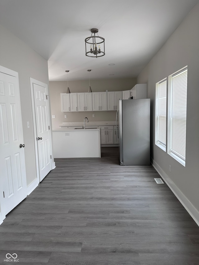 kitchen with stainless steel fridge, dark wood-type flooring, hanging light fixtures, sink, and a chandelier