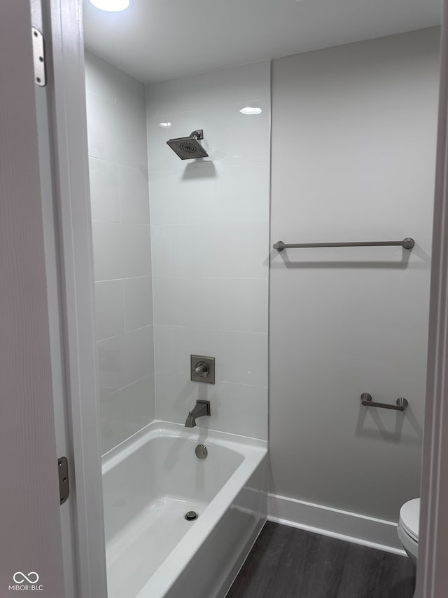 bathroom featuring hardwood / wood-style floors, toilet, and tiled shower / bath combo