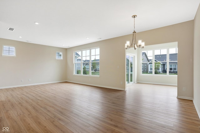 interior space featuring a wealth of natural light, light hardwood / wood-style floors, and a notable chandelier