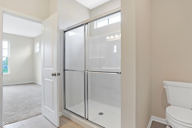 bathroom featuring tile patterned floors, toilet, and a shower with shower door