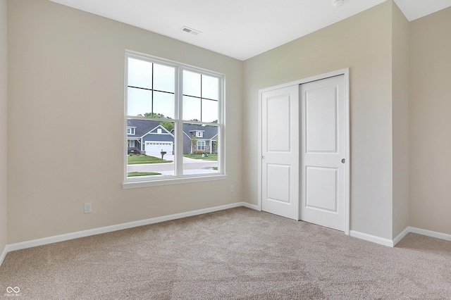 unfurnished bedroom featuring light colored carpet and a closet