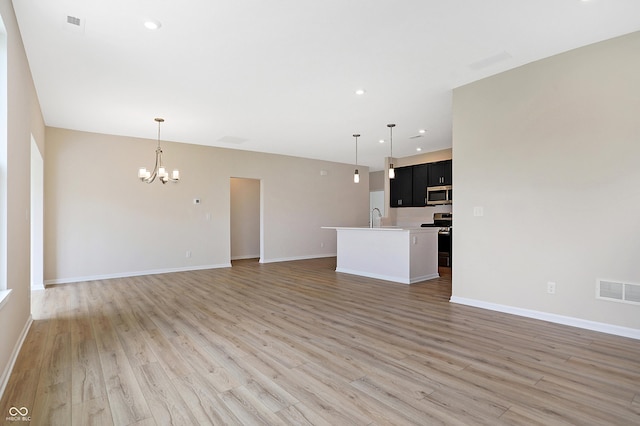 unfurnished living room with sink, hardwood / wood-style floors, and a notable chandelier