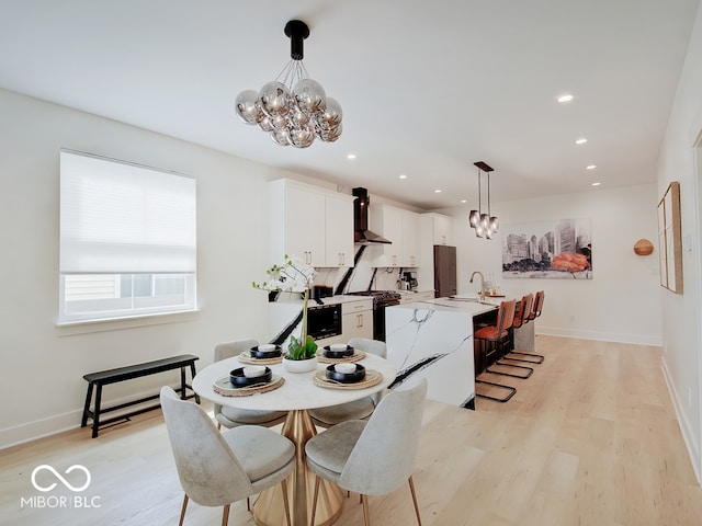 dining room featuring a chandelier, light wood finished floors, baseboards, and recessed lighting