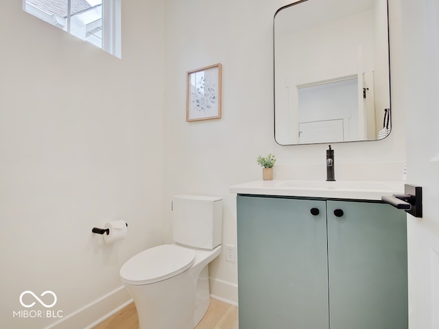 half bathroom featuring baseboards, vanity, and toilet