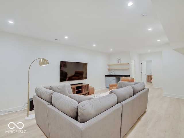 living room with light wood-style floors, recessed lighting, bar, and baseboards