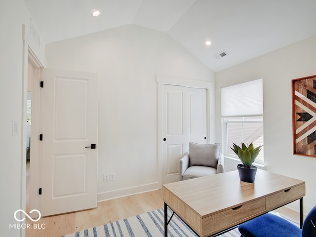 office area featuring lofted ceiling, baseboards, visible vents, and light wood finished floors