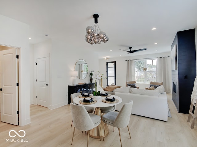 dining room featuring a large fireplace, baseboards, a ceiling fan, light wood-style flooring, and recessed lighting