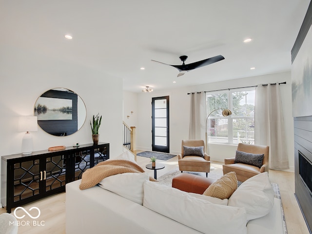 living area with light wood-type flooring, a fireplace, stairway, and recessed lighting