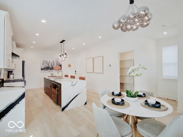 kitchen with light wood-style floors, light countertops, white cabinetry, and a center island with sink