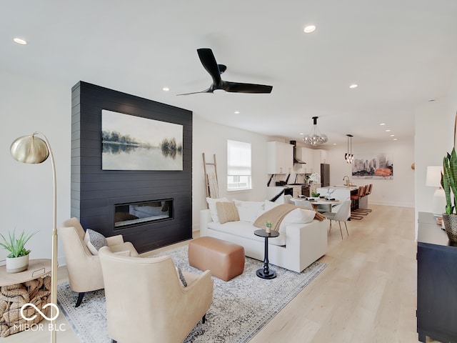 living room featuring a large fireplace, light wood finished floors, baseboards, a ceiling fan, and recessed lighting