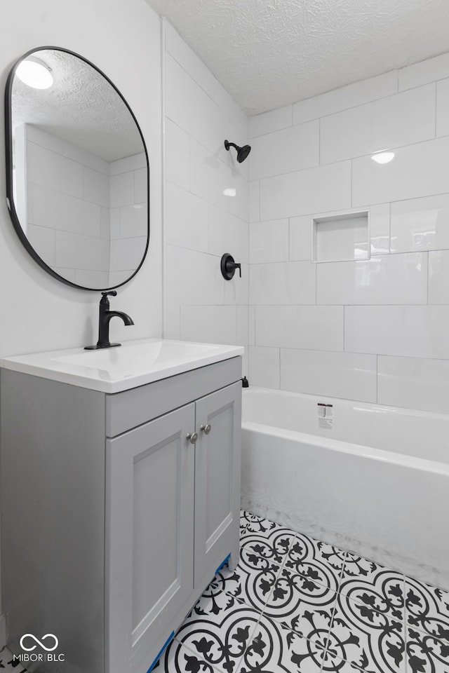 bathroom featuring tiled shower / bath, a textured ceiling, and vanity