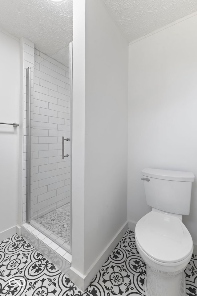 bathroom featuring tile patterned floors, toilet, a shower with door, and a textured ceiling