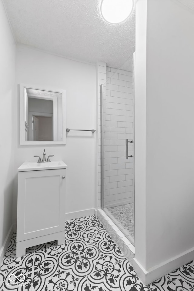 bathroom with a shower with door, vanity, and a textured ceiling