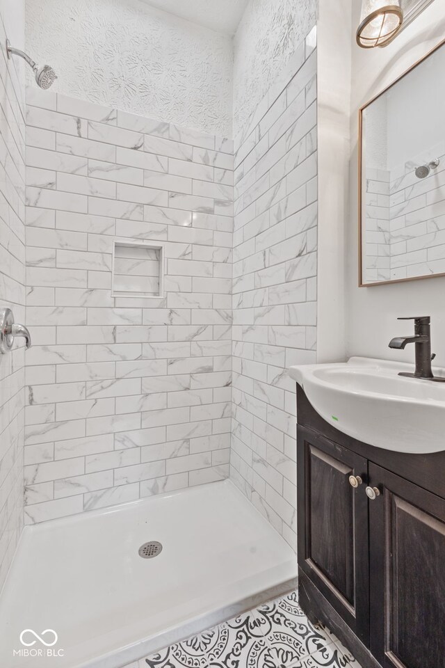 bathroom with vanity, a tile shower, and tile patterned flooring