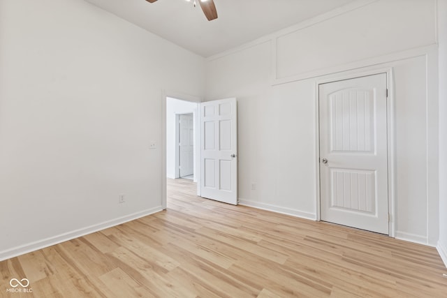 unfurnished bedroom featuring a ceiling fan, a closet, light wood-style flooring, and baseboards