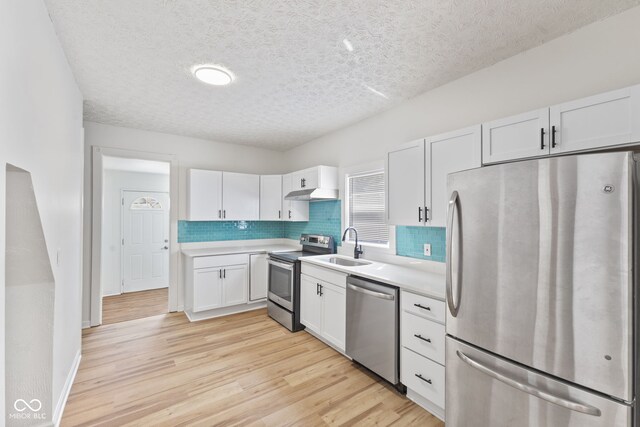 kitchen featuring stainless steel appliances, sink, white cabinetry, and light hardwood / wood-style floors