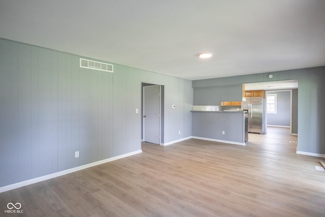 unfurnished room featuring wooden walls and light wood-type flooring