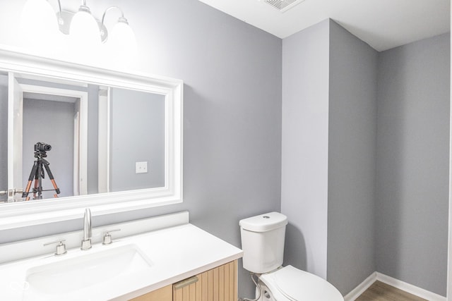 bathroom featuring toilet, hardwood / wood-style flooring, and vanity