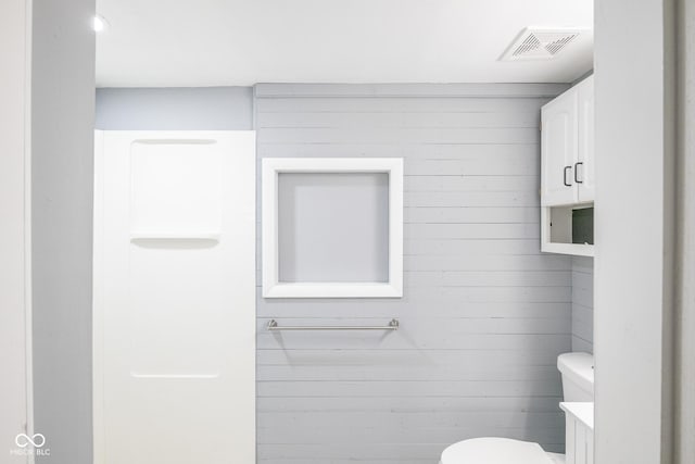 bathroom with toilet and wooden walls