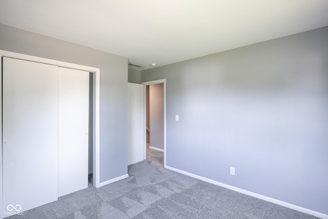 unfurnished bedroom with light colored carpet and a closet