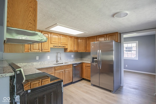 kitchen with light wood-type flooring, sink, stainless steel appliances, and a textured ceiling