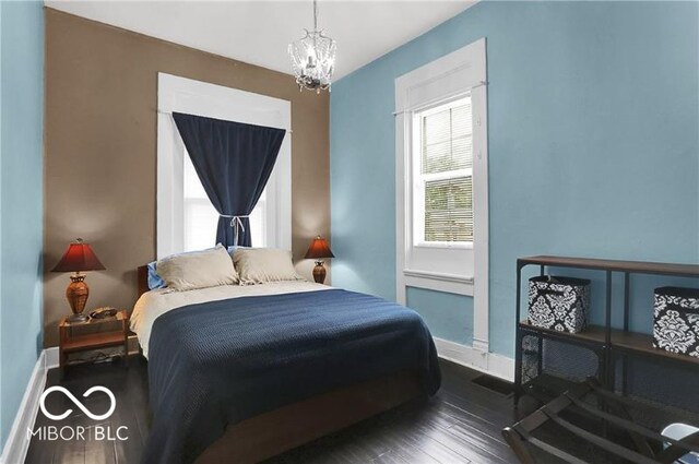 bedroom with a chandelier and dark wood-type flooring